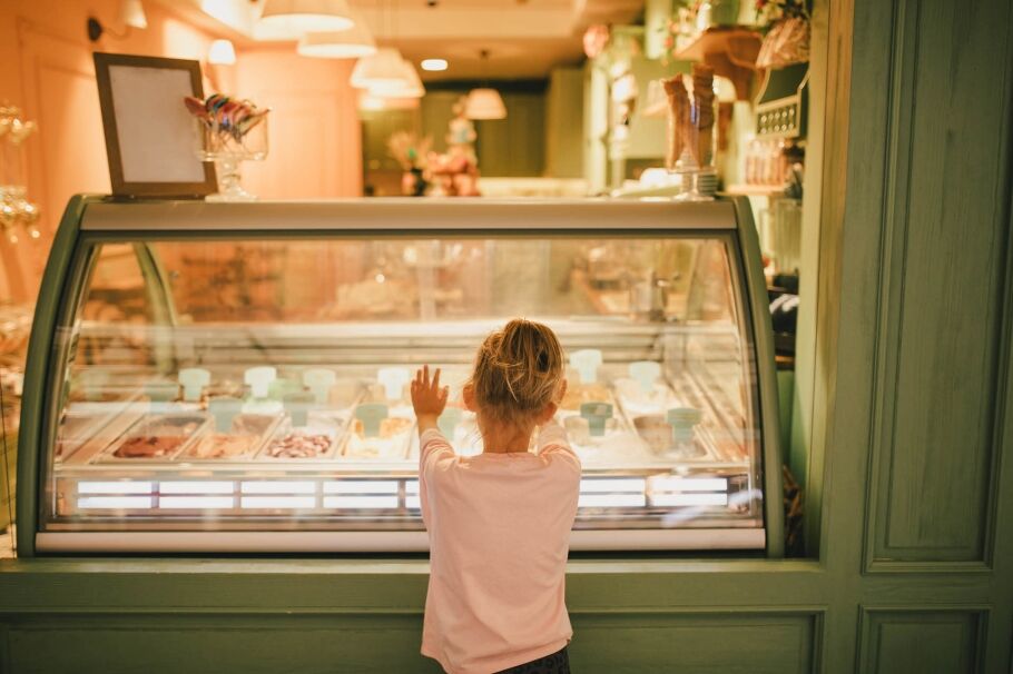 Cute little girl standing near ice-cream shop, choosing ice-cream.