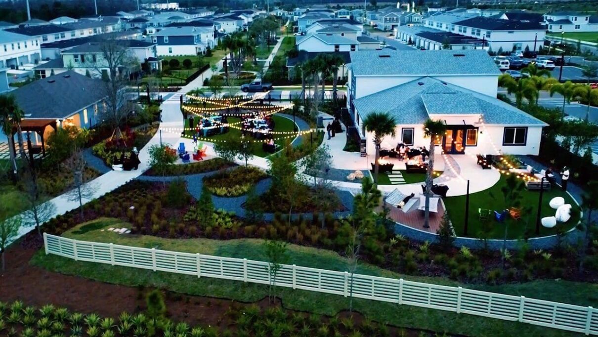 aerial view of EverBe neighborhood at twilight - cafe lights are strung above a green space between two structures where EverBe creates community
